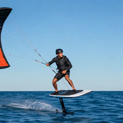 A rider uses a para wing while hydrofoiling across open water on a clear day
