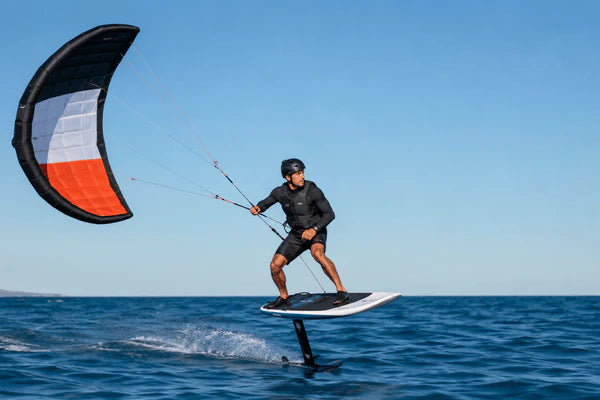A rider uses a para wing while hydrofoiling across open water on a clear day