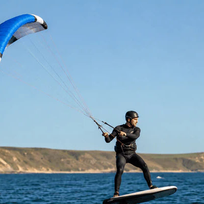 A rider uses a para wing while foiling across open water near a coastline