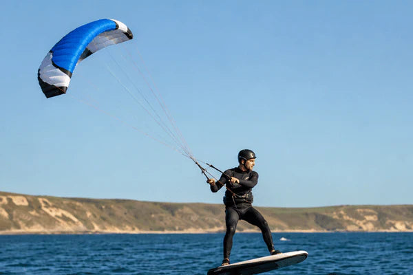 A rider uses a para wing while foiling across open water near a coastline