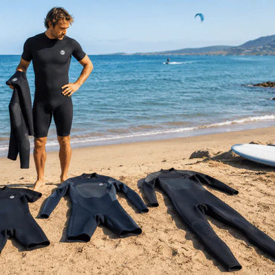 A man compares different wetsuit for men options on a sunny beach before choosing one for summer water sports